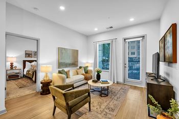 A well-lit living room with a couch, chair, and a painting on the wall.